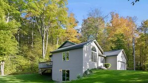 A two-story house with a covered porch, surrounded by a well-maintained lawn and trees.