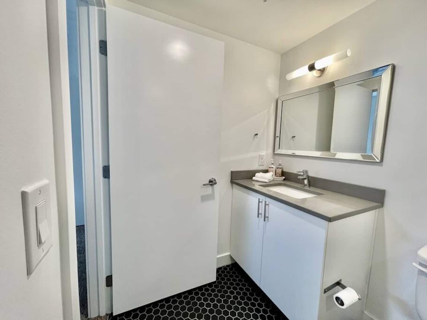 A modern bathroom with a white sink, mirror, and toilet.