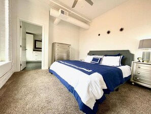 Un dormitorio con cama, cómoda y ventilador de techo.
