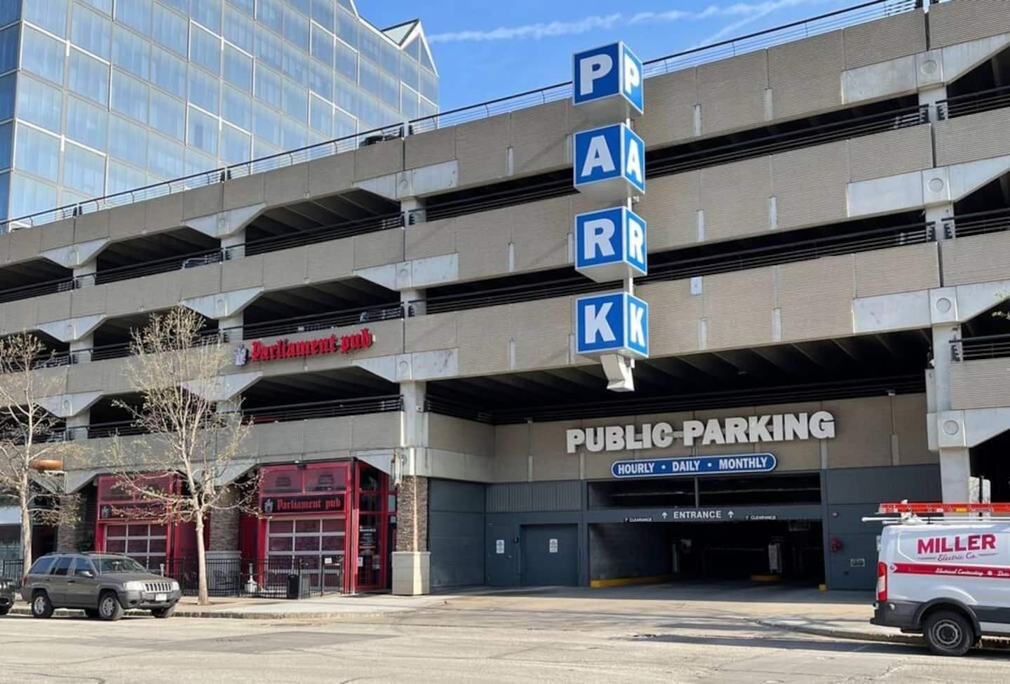 A multi-level public parking garage with a sign indicating hourly, daily, and monthly rates.