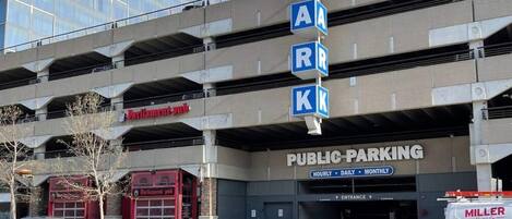 A multi-level public parking garage with a sign indicating hourly, daily, and monthly rates.