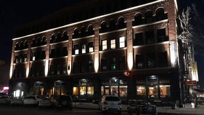 En bygning med flere etager, facade i mursten og oplyste vinduer.