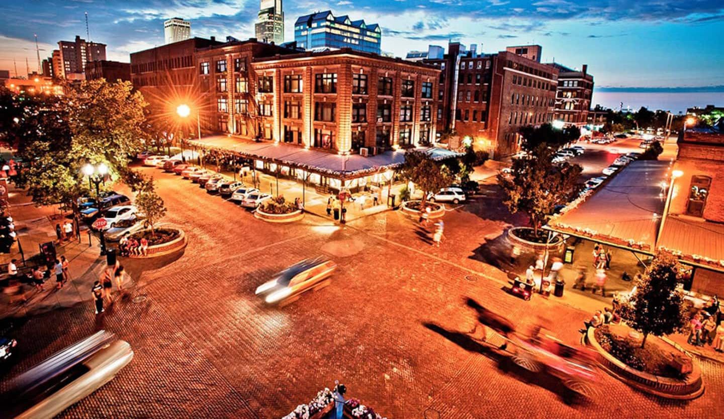 A city square with historic buildings, a tram, and a waterfront view.