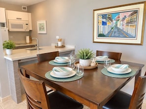 Un comedor con una mesa de madera dispuesta para cuatro personas, con platos, tazones y vasos.