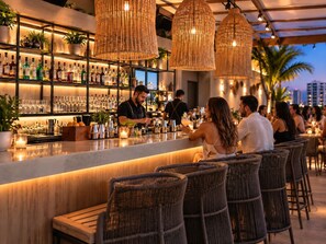 Eine Bar mit Korbstühlen, einer Theke und Regalen voller Flaschen und Gläsern.