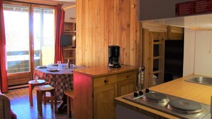 A cozy kitchen with wooden cabinets, a coffee maker, and a dining area with a table and chairs. - 300m from ski slopes, 4th floor, balcony, 23m², Vars (Vars)