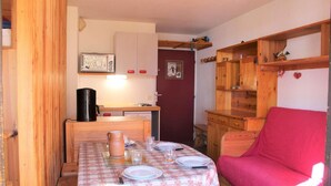 A compact kitchen with wooden cabinets, a coffee maker, and a dining table set for four. - 300m from ski slopes, 4th floor, balcony, 23m², Vars (Vars)