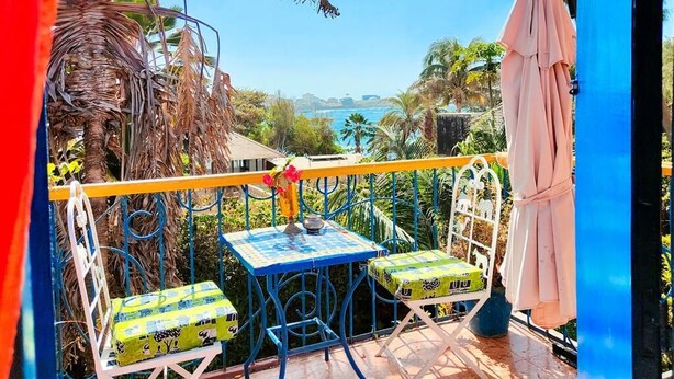 Un balcon avec une table et des chaises, offrant une vue sur la côte.
