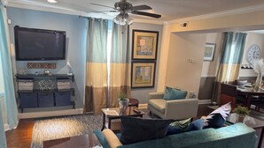 A living room with a sofa, a coffee table, a TV, and a ceiling fan. - Charming 4 Br 2Ba Duplex  (Baltimore)