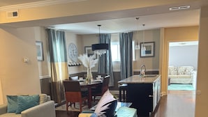 A spacious living room with a blue sofa, a dining area with a table and chairs, and a kitchen in the background. - Charming 4 Br 2Ba Duplex  (Baltimore)