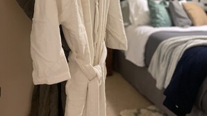 A bedroom with a bed, a nightstand, and a robe hanging on a rack. - Charming 4 Br 2Ba Duplex  (Baltimore)