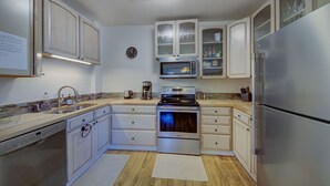 Une cuisine moderne avec des meubles blancs, des appareils en acier inoxydable et un four à micro-ondes.