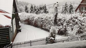 A snow-covered landscape with a house, a wooden fence, and snow-laden trees. - Haus Oseleck, vacation home with 4 apartments and common room with wood-burning stove (Korenov)