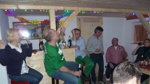A group of people in a room with wooden walls and a bar area. - Haus Oseleck, vacation home with 4 apartments and common room with wood-burning stove (Korenov)
