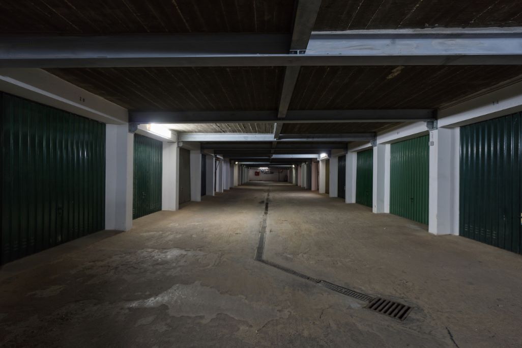 Un largo y estrecho pasillo con puertas verdes a ambos lados, que conduce a un área central abierta.