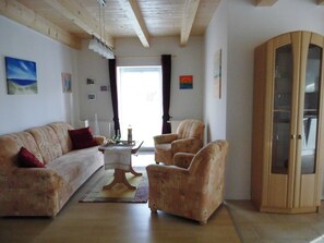 A living room with a sofa, armchairs, a coffee table, and a cabinet.