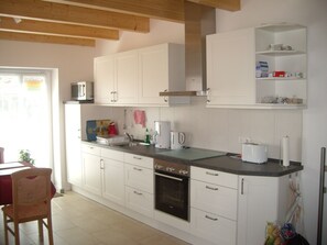 A modern kitchen with white cabinets, a built-in oven, and a countertop with a kettle and coffee maker.