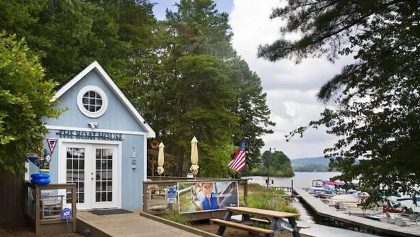 A lakeside building with a dock, a picnic table, and a sign that reads "The Great House." - Lake Arrowhead GA Modern Rustic Private Mountain Cabin Chalet Home (Waleska)