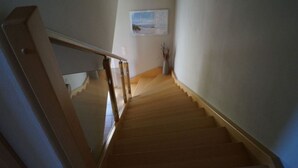 A wooden staircase with a glass railing leading to a landing. - Fantastic FH, terrace, fireplace, close to the Baltic Sea, Bodden view (Fuhlendorf)