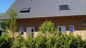 A two-story brick house with a tiled roof, two windows with shutters, and a small skylight. - Fantastic FH, terrace, fireplace, close to the Baltic Sea, Bodden view (Fuhlendorf)