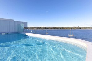Una piscina con vistas al mar y a barcos.