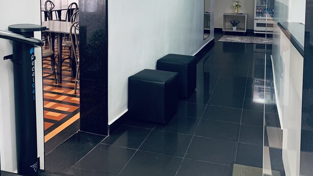 A hotel lobby with a reception desk, a framed photograph on the wall, a staircase, and a seating area. - HOTEL CENTRAL BARAO DO RIO BRANCO  (Anapolis)