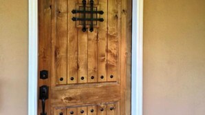 Una puerta de madera con una rejilla metálica central y cerradura a la izquierda.