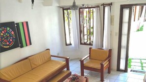 Ein Wohnzimmer mit einer Couch, zwei Sesseln, einem Couchtisch und einem Deckenventilator.