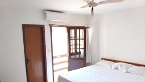 Ein Schlafzimmer mit einem Bett, einem Deckenventilator, einem Fenster mit Vorhängen und einer Tür.