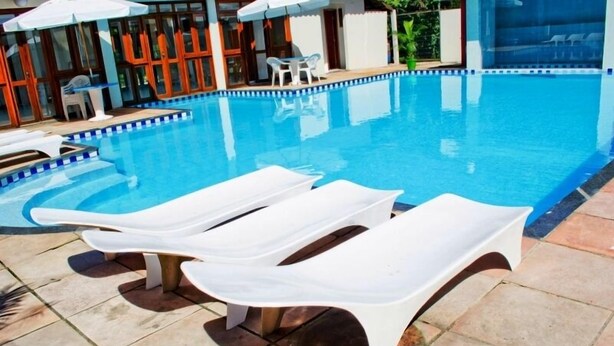 Ein Swimmingpool mit weißen Liegestühlen und einer gefliesten Liegefläche.