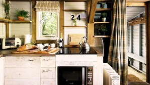 A rustic kitchen with wooden beams, a number 24 sign, a toaster, a kettle, and a microwave.