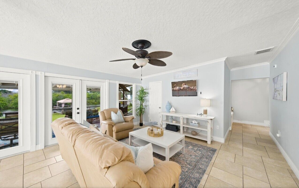 Un salon spacieux avec un canapé beige, une table basse et un ventilateur de plafond.