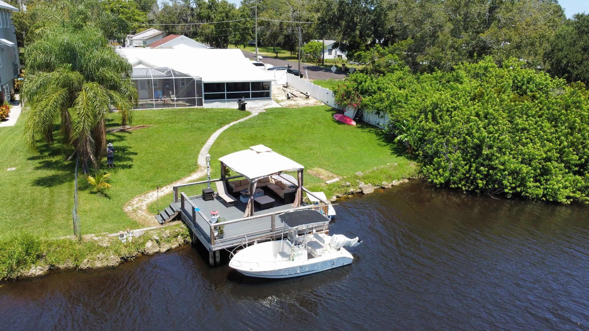 A house with a large deck and a boat docked by a waterway.