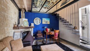 A room with a fireplace, a blue wall, a staircase, and a wooden ceiling.