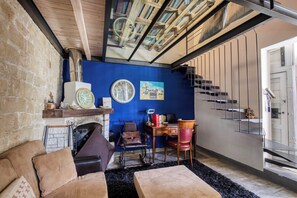 A room with a fireplace, a blue wall, a staircase, and a wooden ceiling.