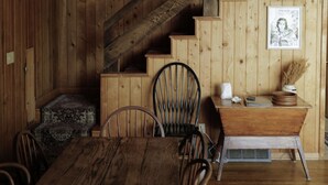 Un interior de madera con una mesa de comedor, sillas, una escalera y un cartel en la pared.