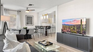 A modern living room with a sofa, coffee table, and a TV displaying a desert landscape.