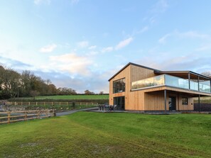 A modern two-story house with a wooden exterior and large windows. - Fron Haul - Robin Goch (Ruthin)