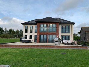 A modern two-story house with a patio area featuring outdoor seating and a barbecue grill. - Ty Marlyn (Swansea)