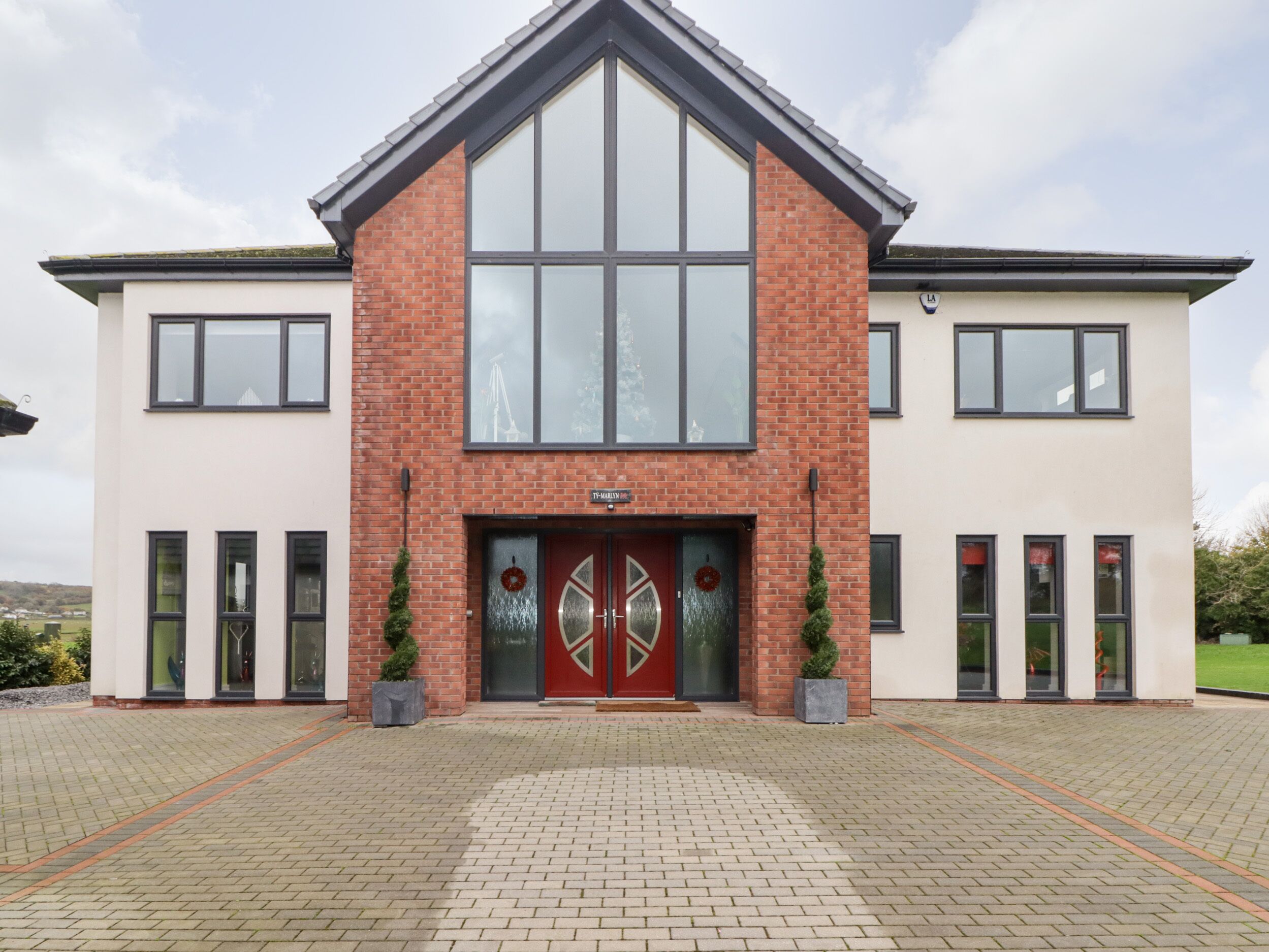 A modern building with a symmetrical facade, large windows, and a prominent entrance with a double door and a wreath.