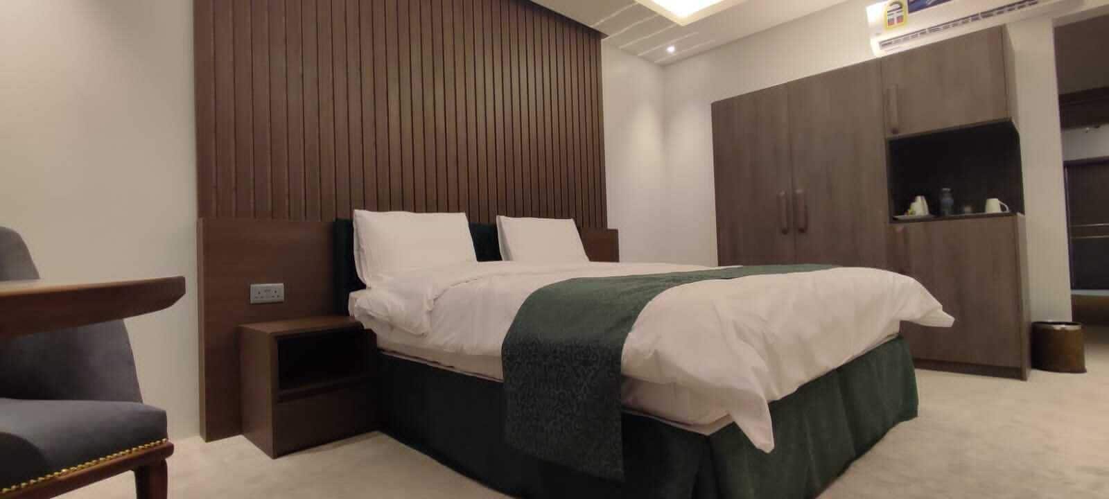 A neatly arranged bedroom with a bed, bedside table, and wardrobe.