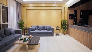 A modern living room with a grey sofa, a coffee table, and a reception desk. - GREEN VIEW HOTEL (Sayq)