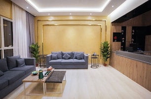Una sala de estar moderna con un sofá gris, una mesa de centro y un mostrador de recepción.