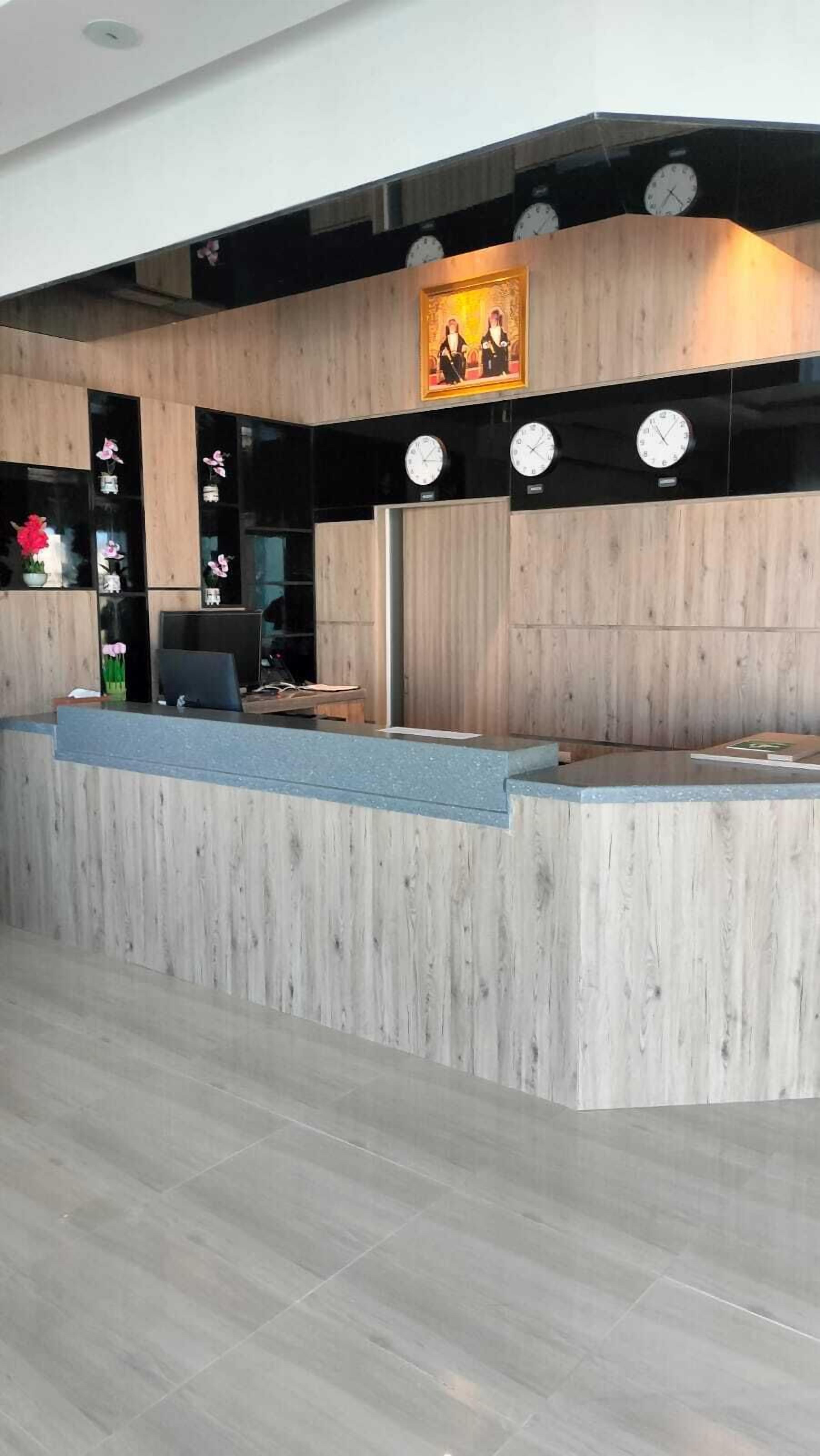 A reception desk with a wooden finish, a clock above it, and a framed picture on the wall.