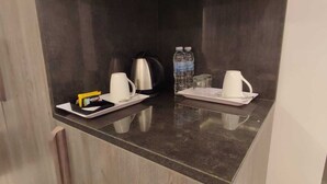 A kitchen counter with a coffee maker, two cups, a water bottle, and a glass. - GREEN VIEW HOTEL (Sayq)