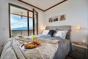 Enjoy a restful stay in this inviting bedroom with a large bed, breakfast tray, and scenic views.