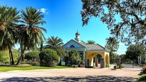 A small, yellow church with a bell tower, surrounded by palm trees and a paved driveway. - Providence Golf & Country Club Executive Pool Home - Located Near Disney (Davenport)