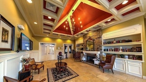 A spacious lobby with a high ceiling, a fireplace, and a bookshelf. - Providence Golf & Country Club Executive Pool Home - Located Near Disney (Davenport)