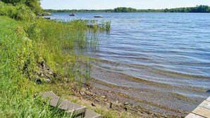 A lakeside view with boats, a dock, and surrounding greenery.