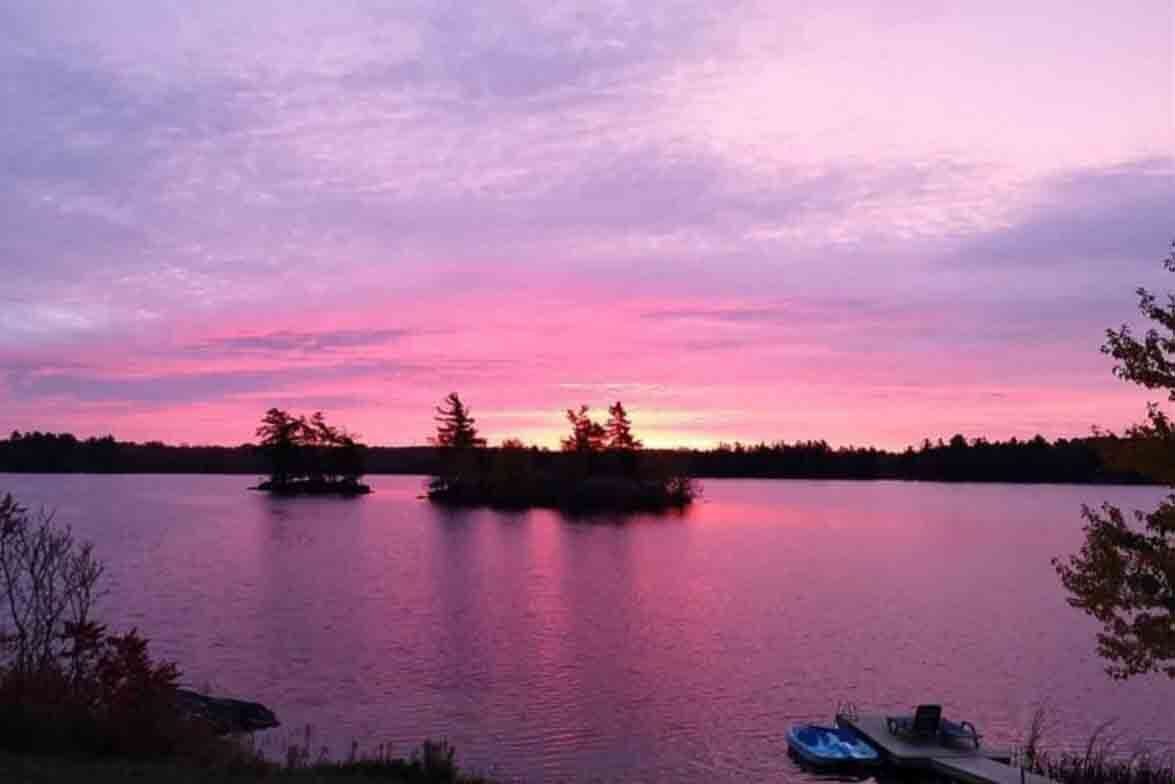 Un lac paisible au coucher du soleil, avec des bateaux amarrés près du rivage.